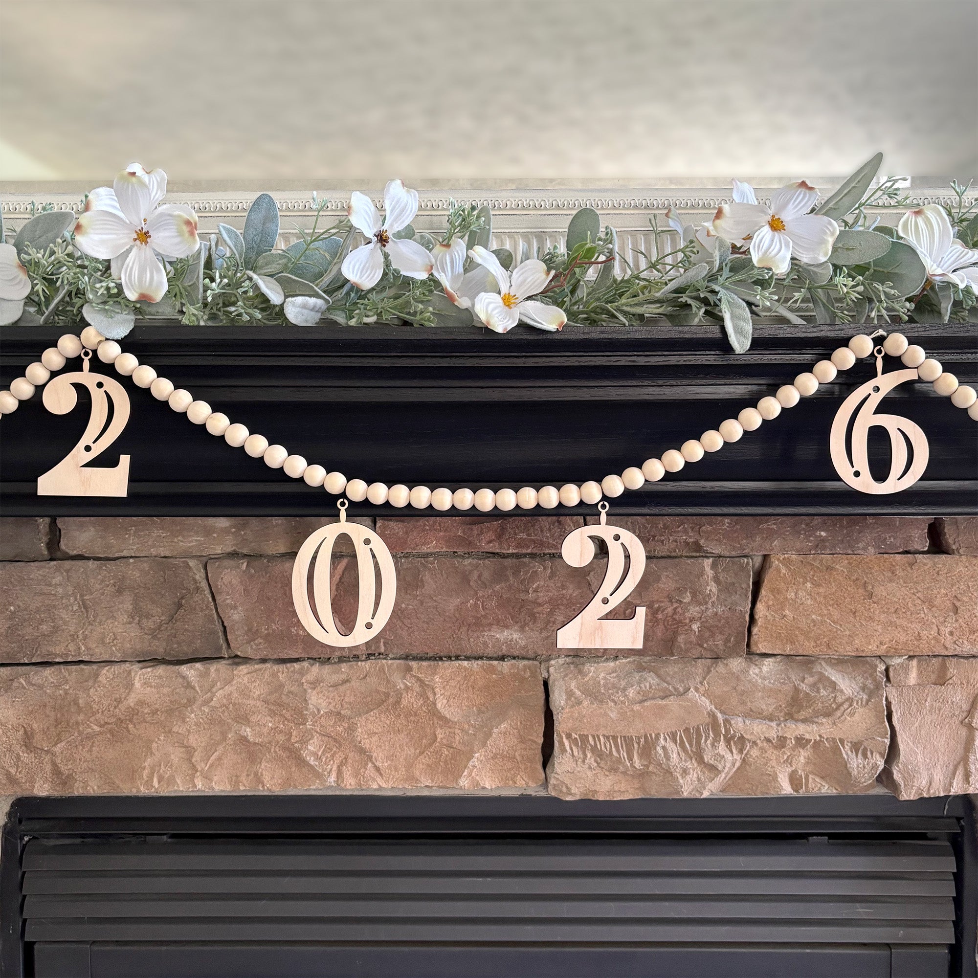 2026 Graduation decoration on fireplace mantel. Garland is made from wood beads with laser cut wood charms that read 2026.