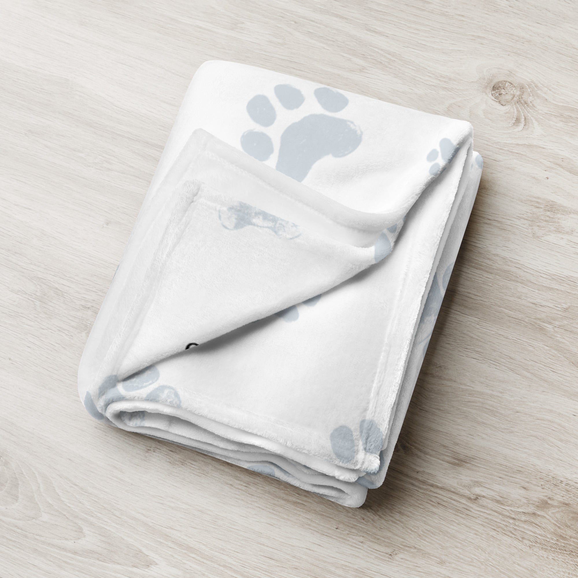 Folded blanket with blue paw print pattern. Blanket has text that says, “snuggles from Luna.” Sympathy gift for loss of pet.