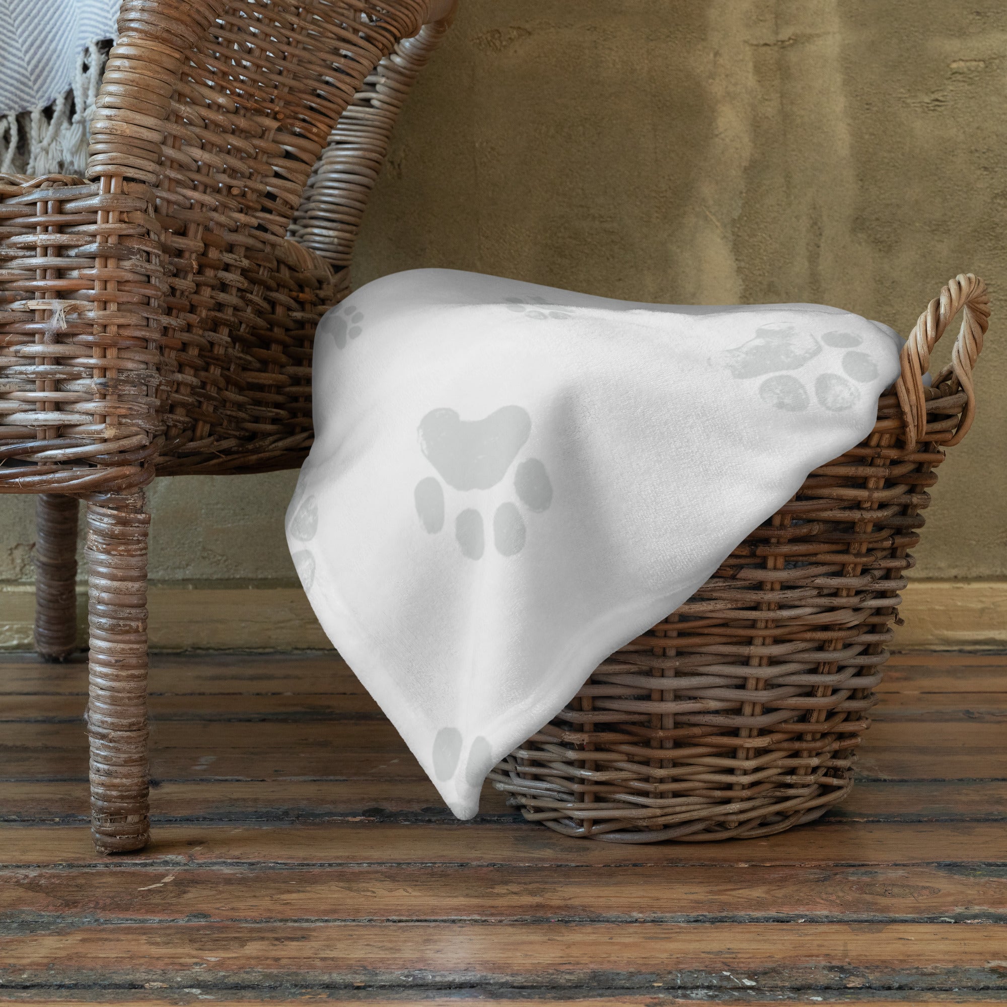 Blanket with a gray paw print pattern in basket. Blanket has text that says, “snuggles from Zeke.” Sympathy gift for loss of dog or cat.