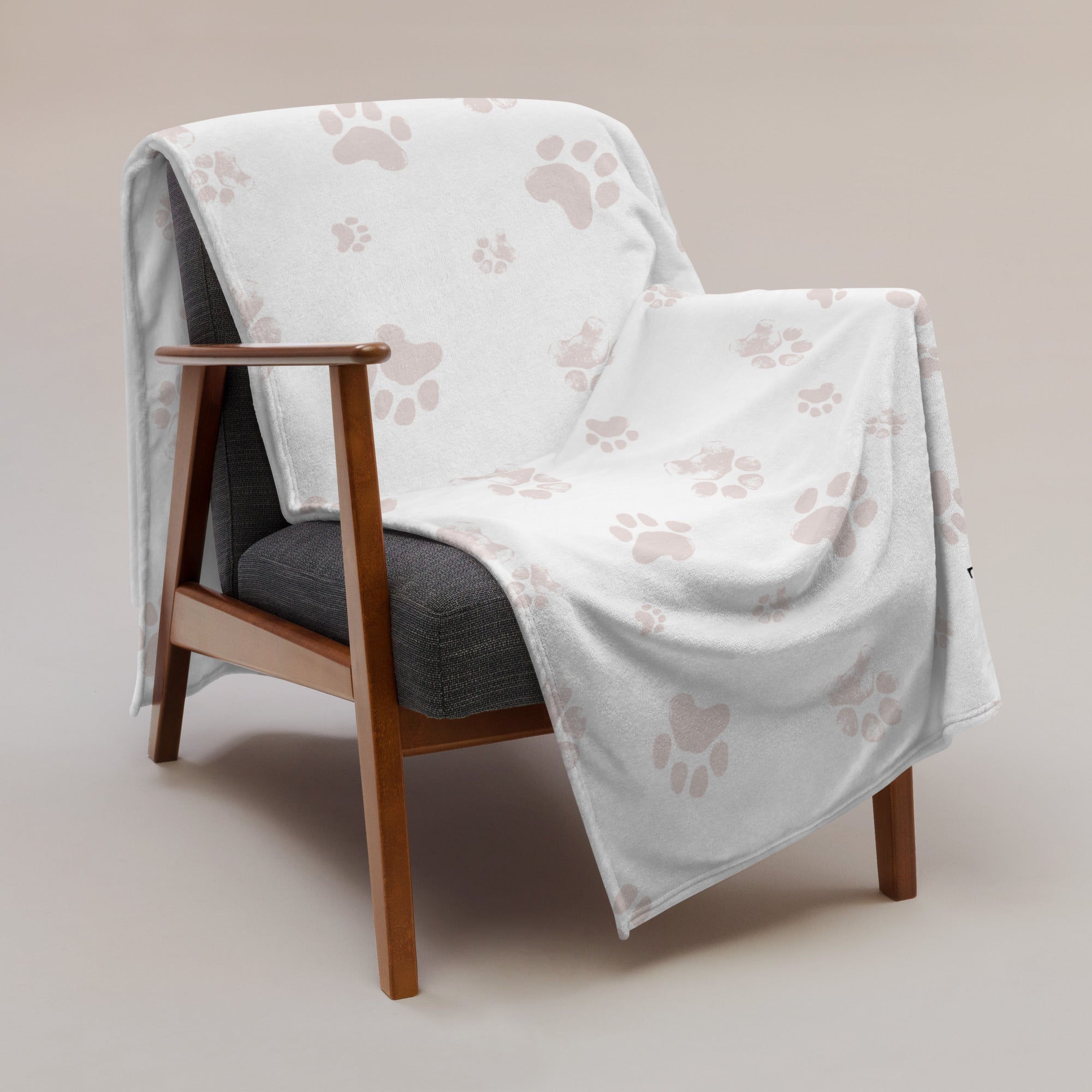 Personalized memorial blanket with pink paw print pattern draped over a chair. Blanket has text that says, “snuggles from Millie.” Sympathy gift for loss of cat.