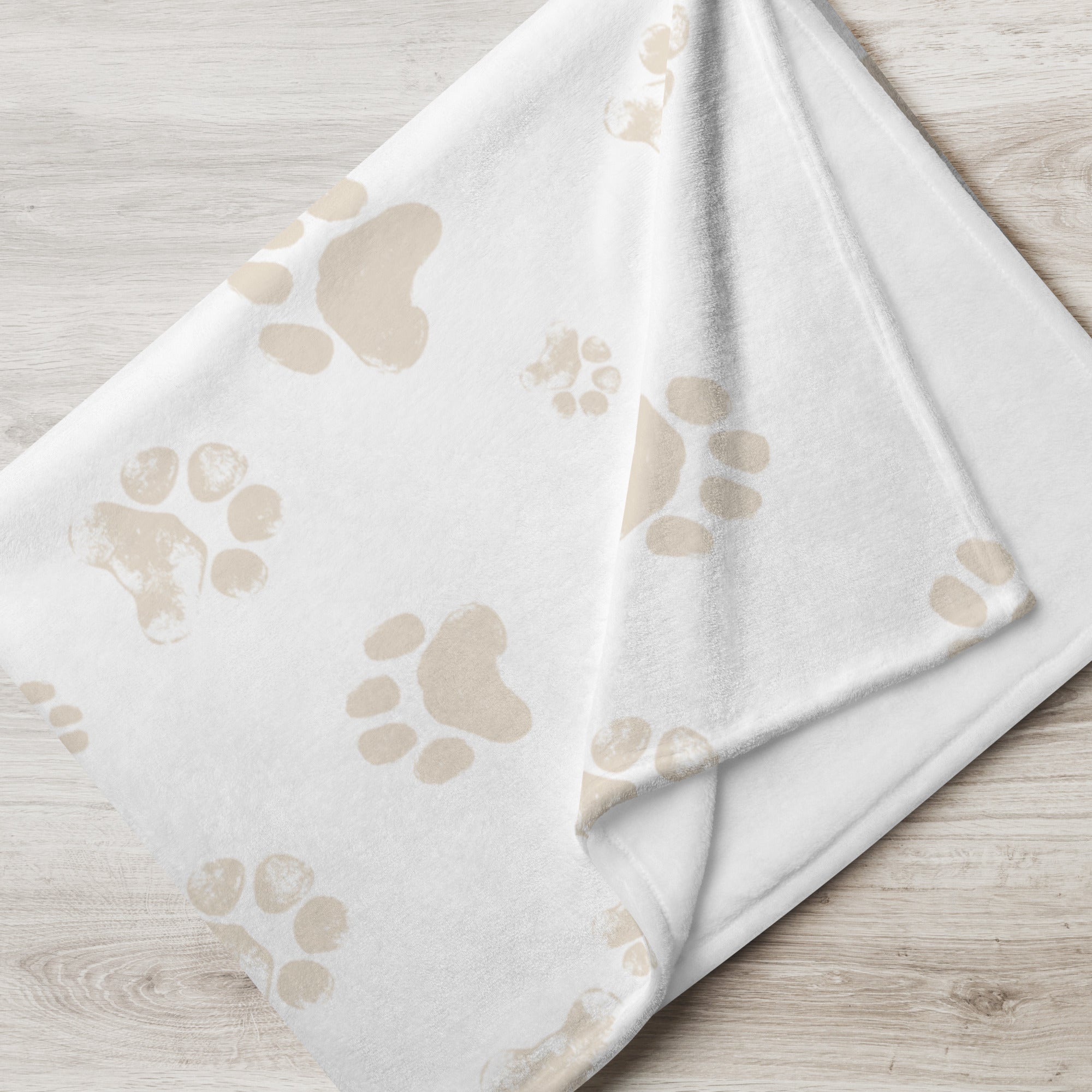 Folded blanket with pale taupe paw print design. Blanket has text that says, “snuggles from Shelby” Sympathy gift for loss of cat or dog.