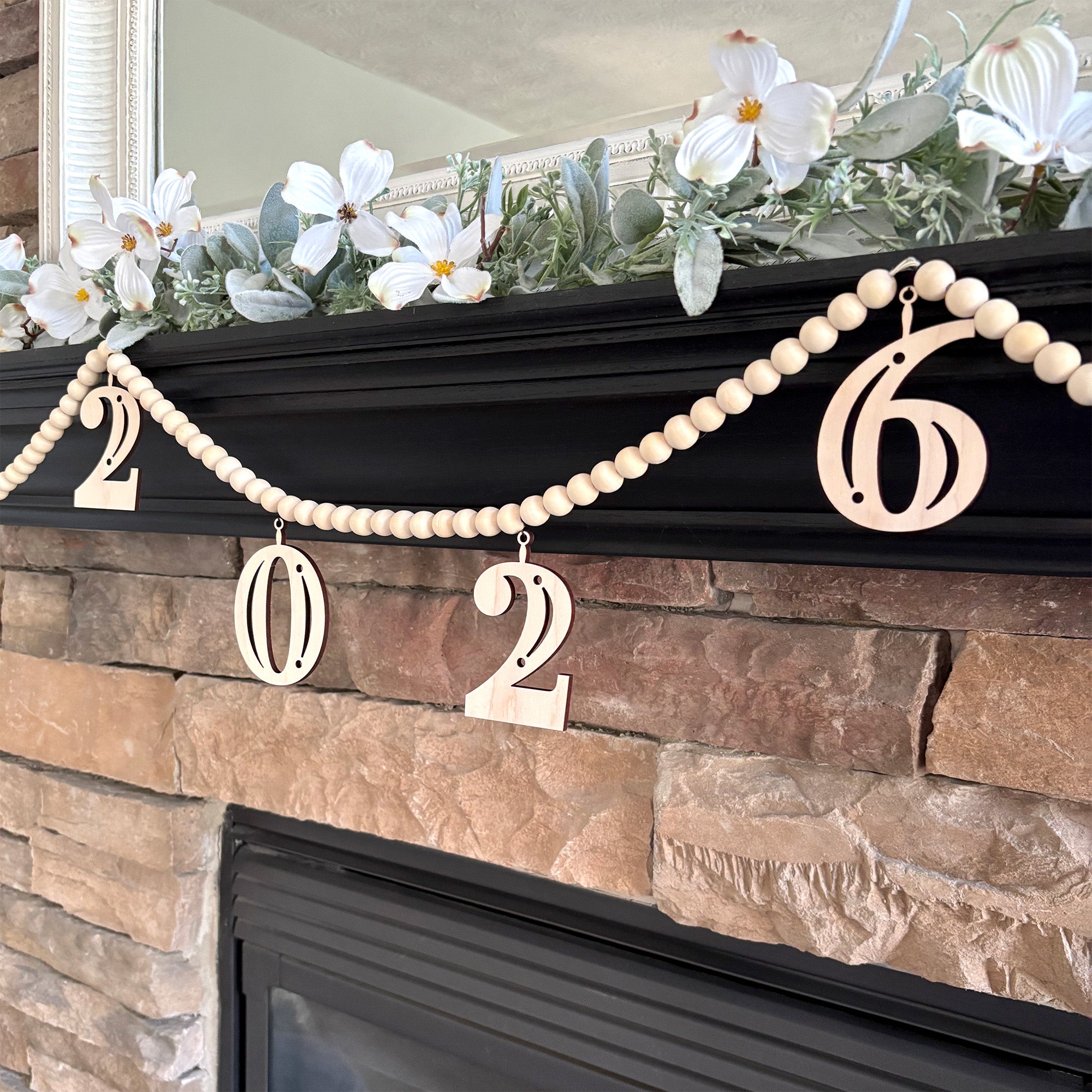 2026 Graduation decoration on fireplace mantel. Garland is made from wood beads with laser cut wood charms that read 2026.
