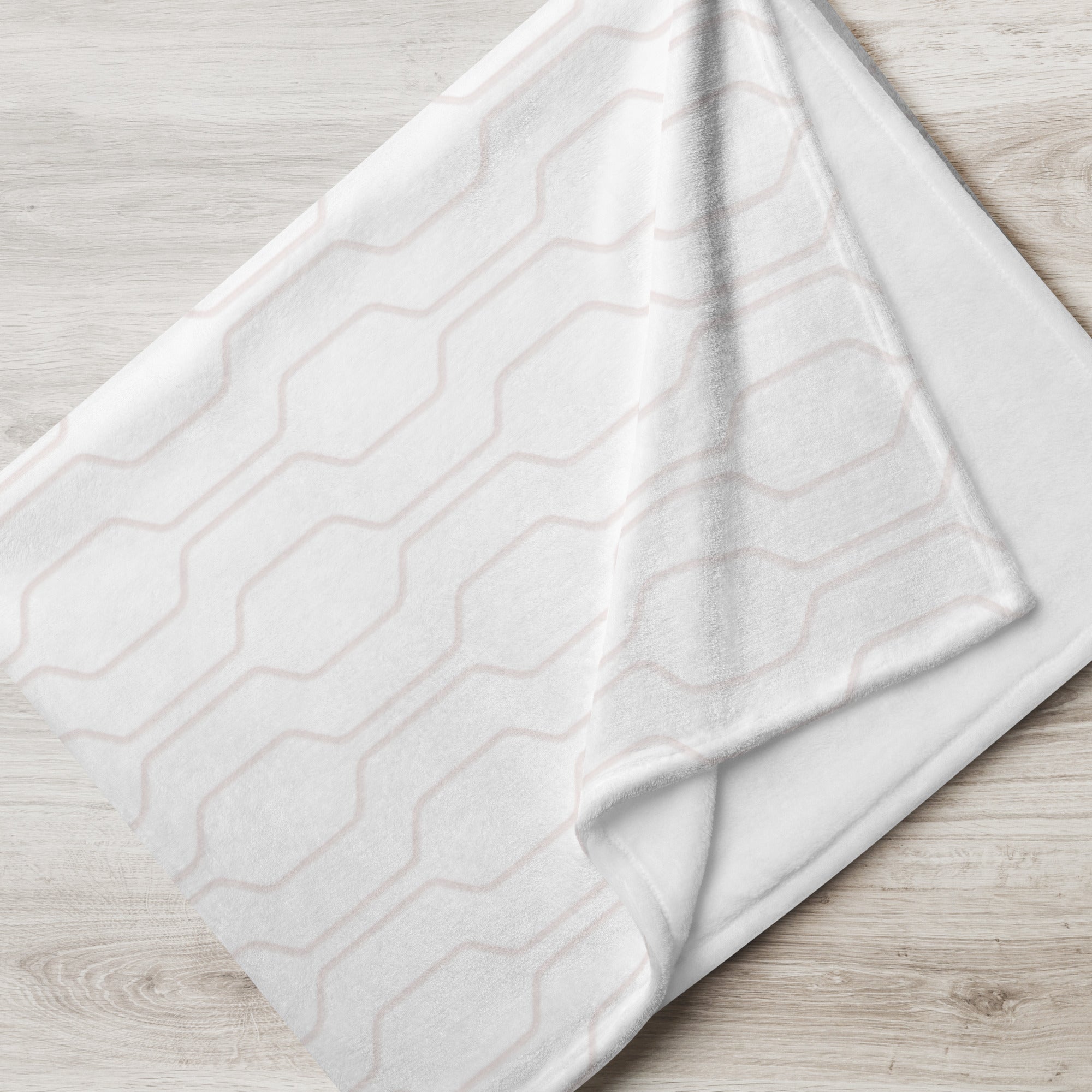 Folded blanket with pale pink mid century modern pattern. Blanket has text that says, "a hug from Elise.” Sympathy gift for loss of child.
